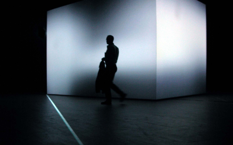  In a completely dark room, there is a 3.5 meter high cube whose shape is distorted by a light projection. In front of it, the shadow of a man ..
