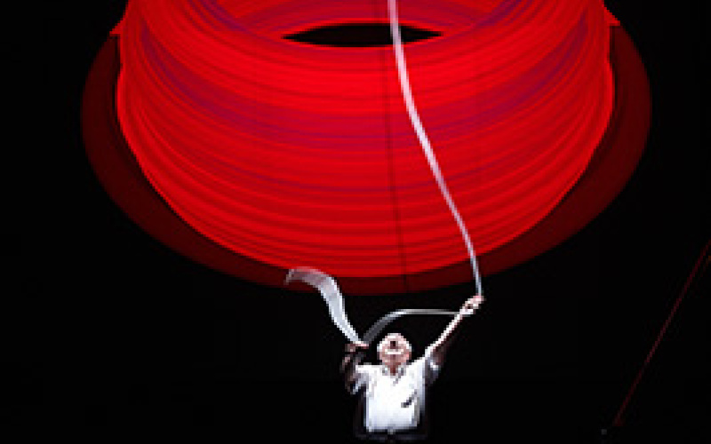 A man handle a huge red ring in front of a black background