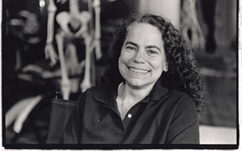 B/W photography. Portrait of a woman. In the background, a human skeleton.