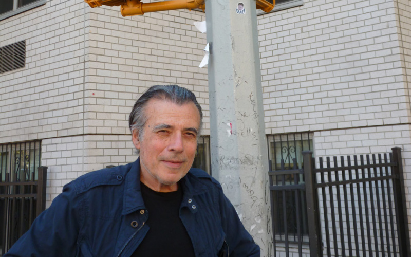 Ein Mann steht an einer Straßenecke unter einer Ampel, auf der eine rote Hand abgebildet ist
