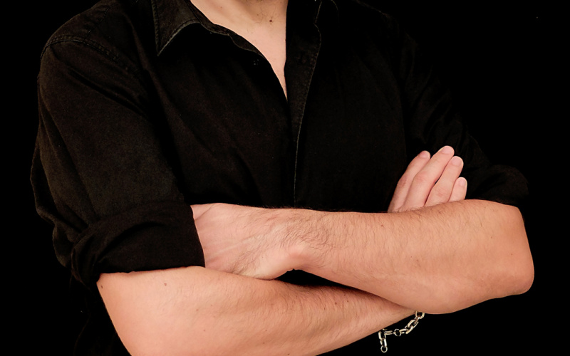 Ein Mann in schwarzem Hemd mit verschränkten Armen