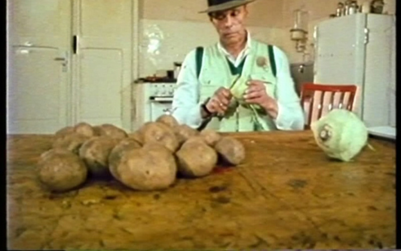 A man sitting at a table and peels potatoes and turnips