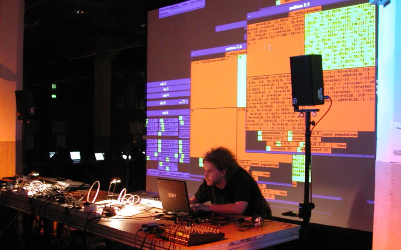 A software developer in his work. The viewer can on a large video screen visually watch the programming.