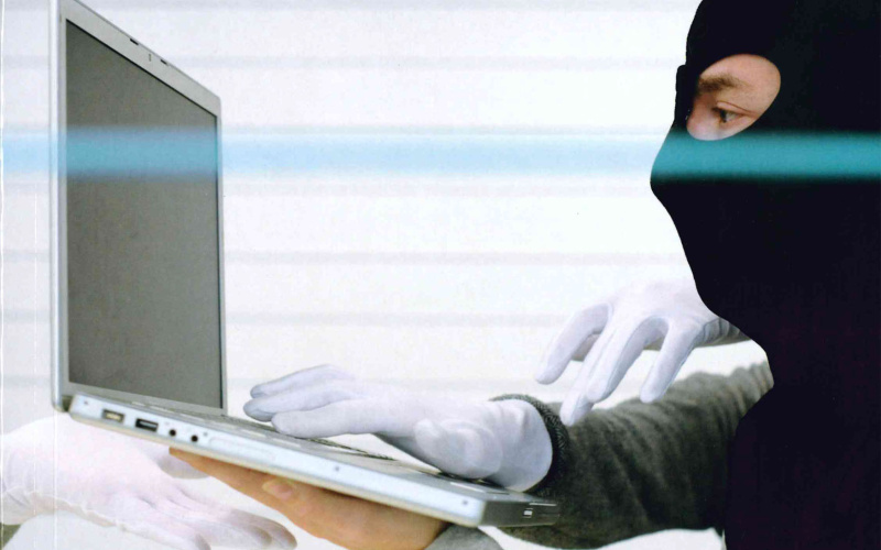 Bookcover with photo: Man with a black balaclava in front of a laptop