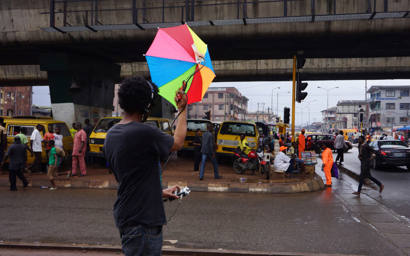 A man with a colorful umbrella records ambient noise on a busy street