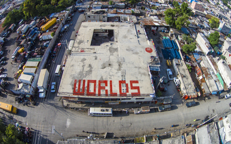 Das Wort "Worlds" in großen roten Buchstaben auf einem Flachdach in Haiti, Sicht von oben