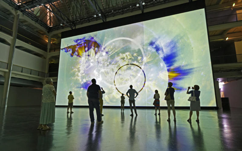 People are photographing and looking at the large-scale wall-installation of Ryoji Ikeda