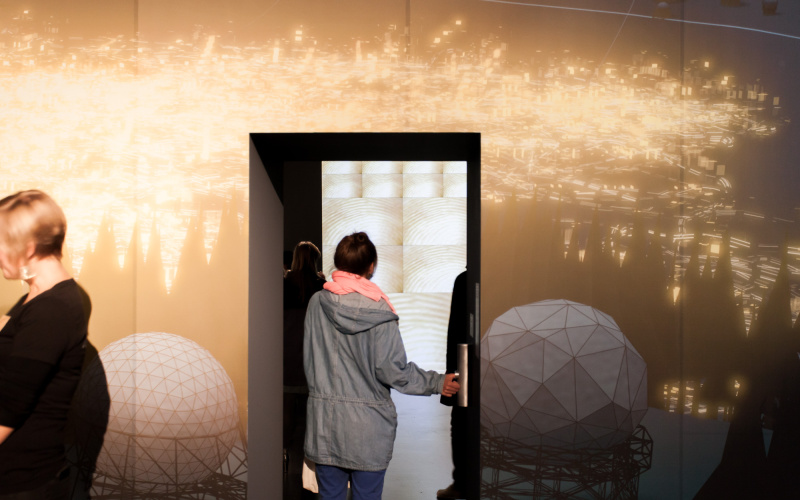 A woman walks through a door on which a video is projected
