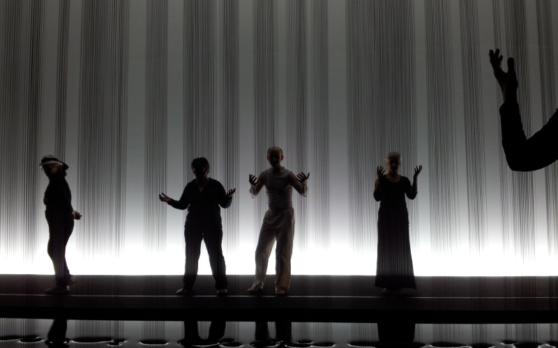 Danceworkshop in the exhibition infront of a sculpture at which streams of oil are running from the ceiling to the floor.