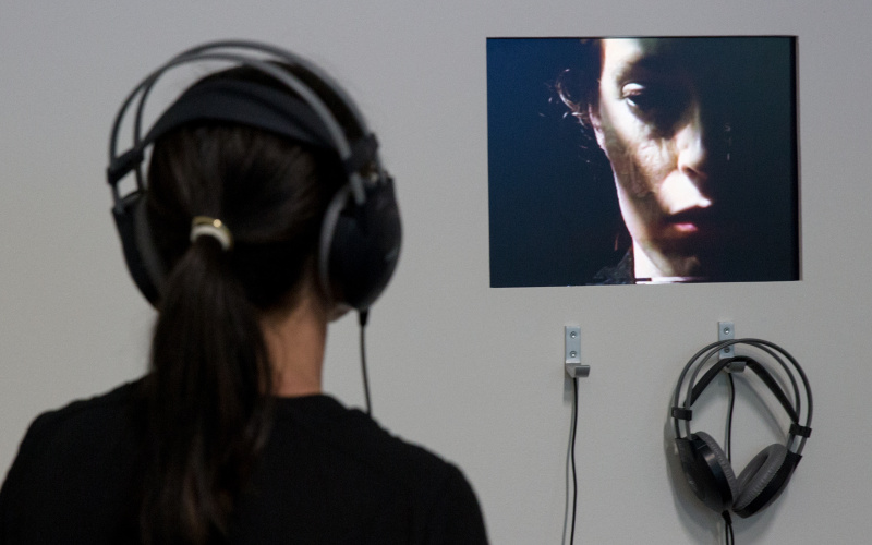A woman with headphones is watching a video of another woman.