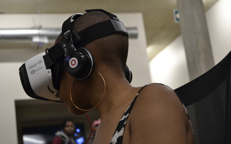 Shoulders and head af an african woman wearing VR goggles