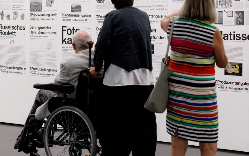 Das Bild zeigt drei Besucher vor Plakaten mit Typografie 