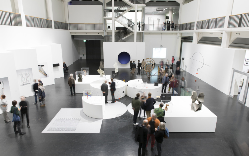 Many people are in Lichthof 8 and look at the artworks of the exhibition »Negativer Raum«.