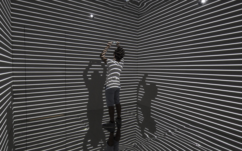 Man in a room which is striated by light.