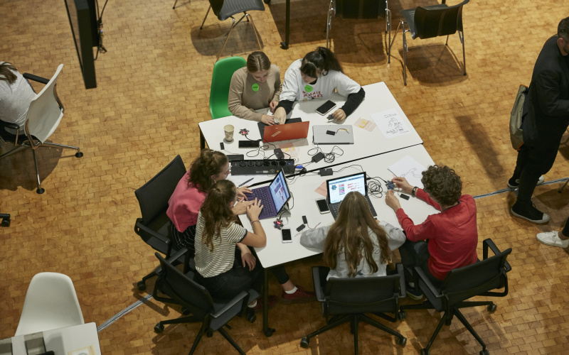 An einem Tisch sitzen mehrere Jugendliche und arbeiten an Projekten