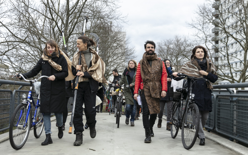 Eine Gruppe von Menschen gehen in einer Prozession mit Fahrrädern.
