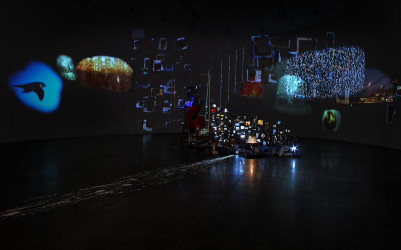 Foto eines dunklen Ausstellungsraumes mit Lichtreflexionen.