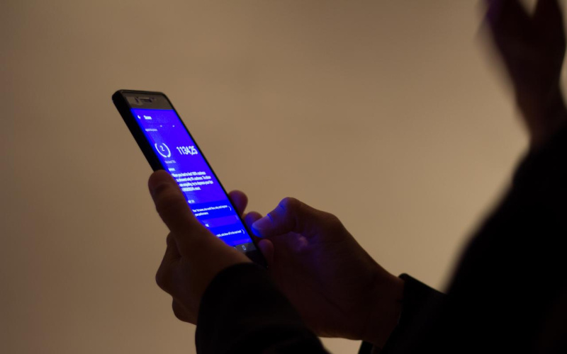 Hände bedienen ein Handy mit einem blauen Bildschirm