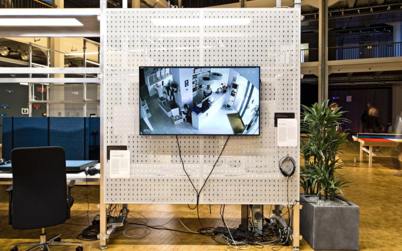 The exhibition view shows a screen with a room shot on a partition wall