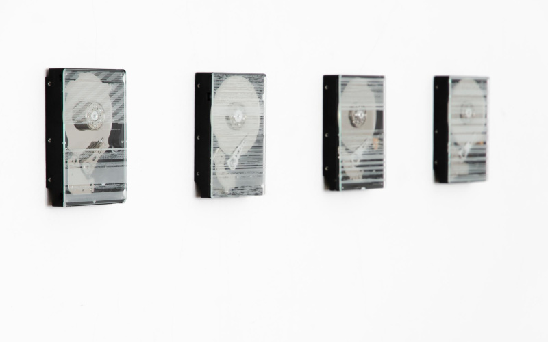 Vier Festplatten hängen in einer Reihe an der Wand. Sie sind mit einem Glas überdeckt, welches Gravierungen aufweist