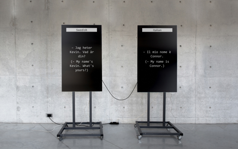 The picture shows two large screens: one translates to Swedish and the other to Italian