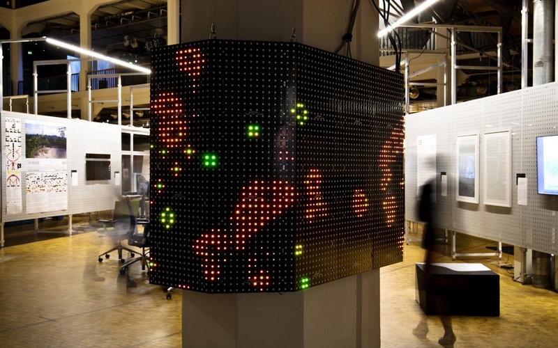 Abbildung des Werkes »Game of Life«, Lichtpunkte auf einem um die Säule verlaufenden Screen