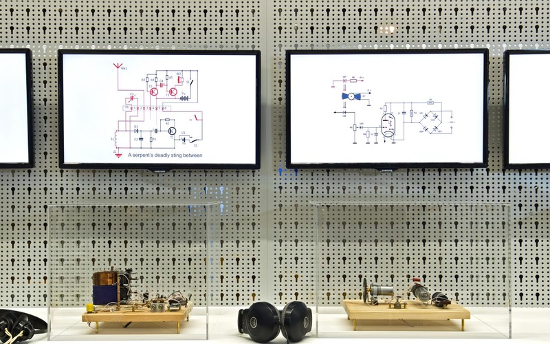 Installation mit Bildschirmen, Kopfhörern und kleinen Apparaturen