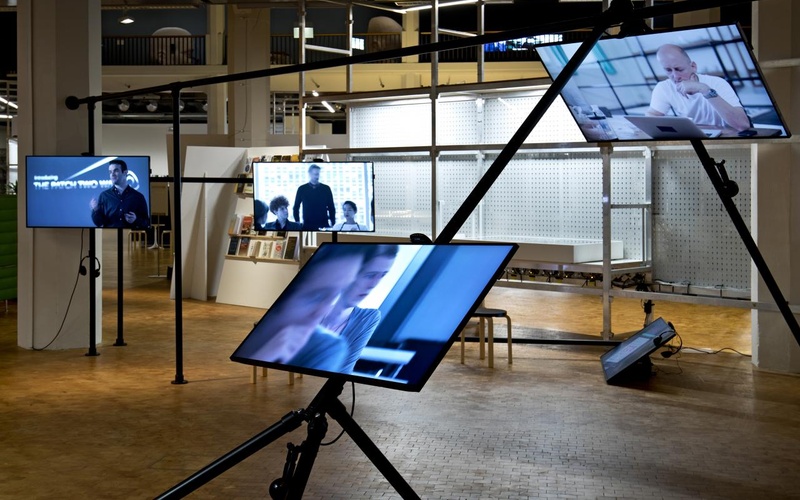 Installation mit mehreren Bildschirmen auf einem schwarzen Gerüst