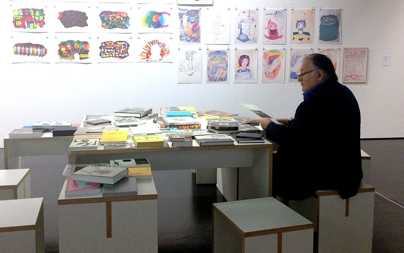 Peter Weibel sits at the ZKM at a table with books