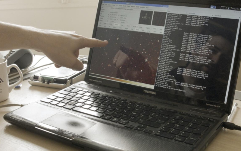 A male hand points to a computer screen