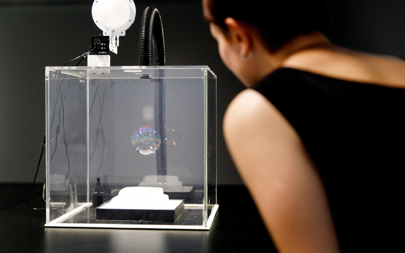 The photo shows the work of Verena Friedrich in a close-up. A profile of a person can be seen blurred on the right side of the picture.