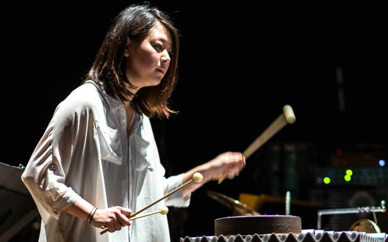  Woman with white shirt playing with drumsticks on percussion