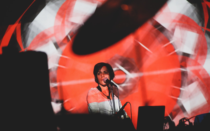 A woman at the microphone, in front of her red-white light projections.