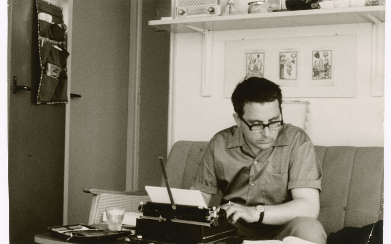Theo Lutz sitz in einem Arbeitszimmer auf der Couch und arbeitet an der Schreibmaschine.