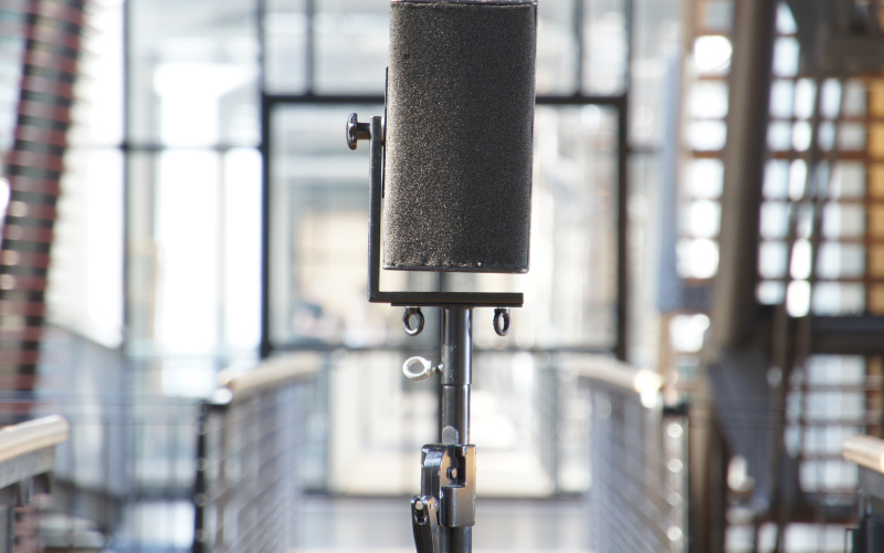 Das Foto zeigt ein zylinderförmiges Mikrofon mit silberenem Ständer.