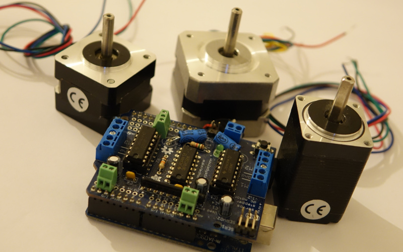 Three stepper motors and a circuit board are connected with multicolor wires.