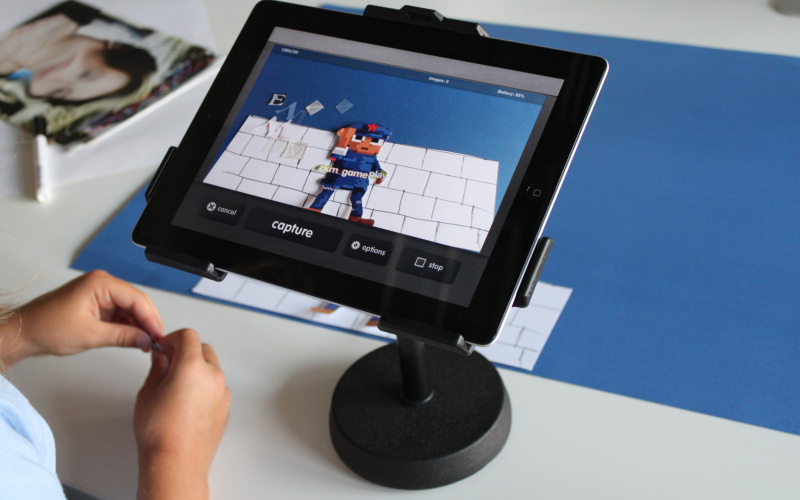 Man sieht zwei Kinderhände, die an einer Papiercollage arbeiten, die mit dem iPad zum Stop-Motion-Trickfilm wird. 