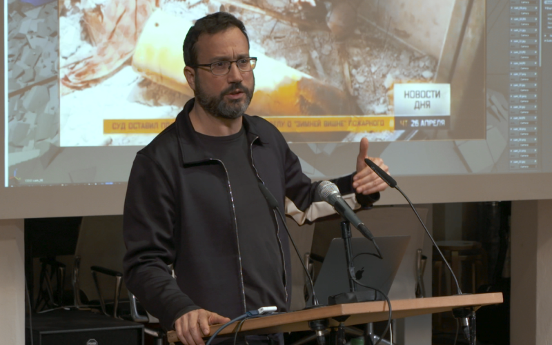 Eyal Weizman, a man with a beard and specs giving a lecture in front of a screen.