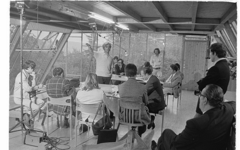 Eine alte schwarz-weiß Aufnahme des Architekten Frei Otto, der in einem Kreis von Zuhörern steht