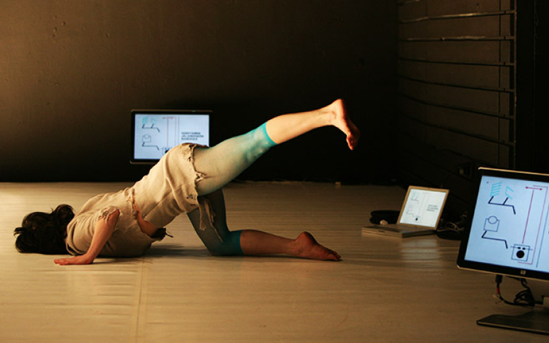 A woman lies with her head towards the floor, while she lifts up her left leg