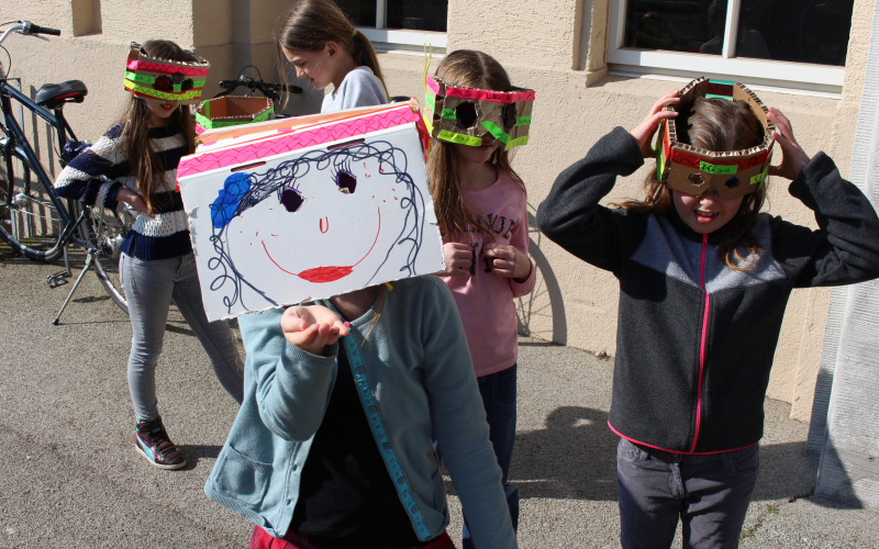 A group of girls made themselves masks out of ordinary items. They are standing in front of the building of the ZKM.