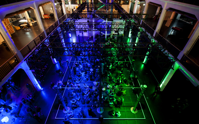 Das Bild zeigt das vollgefüllte, grün und blau beleuchtete ZKM-Foyer