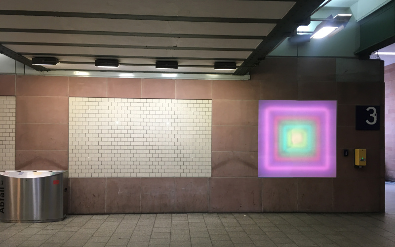 You can see the passage underneath the Karlsruhe main station. A luminous square is attached to the wall, which has a color gradient from inside to outside, creating a depth.