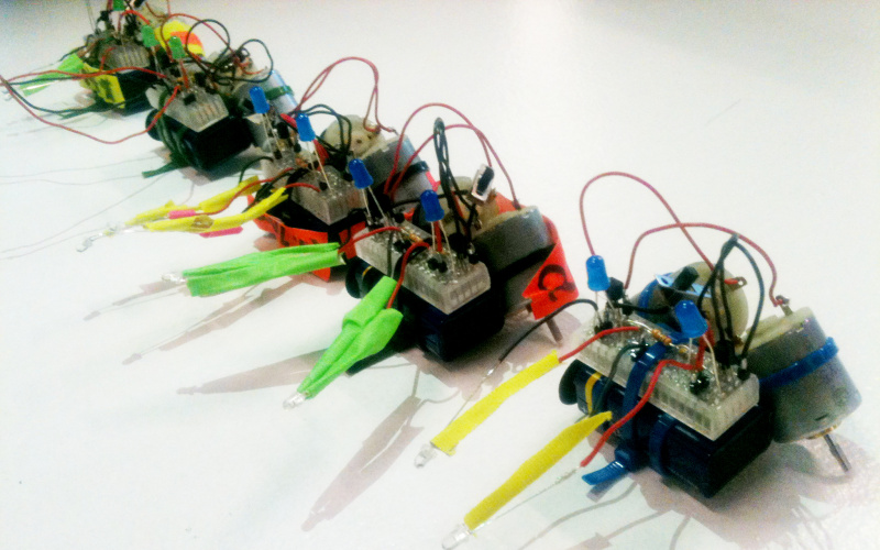 Five little T2-R2-robots out of electronic parts that are held together by ziptie