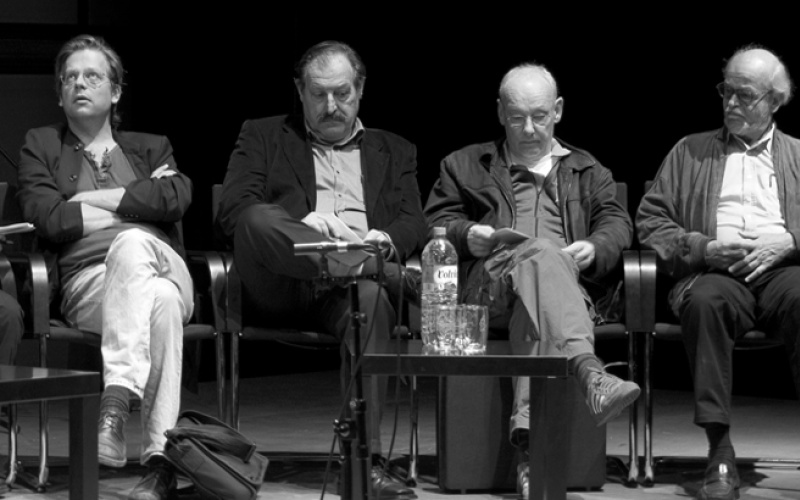 Vier Männer sitzen nebeneinander auf einer Bühne