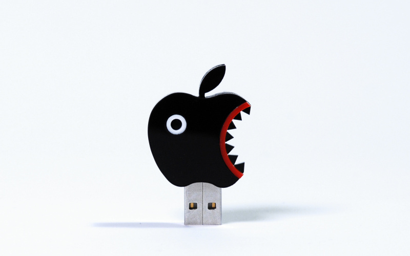 Das Foto zeigt einen USB Stick als schwarzer PacMan ähnlicher Apfel getarnt. 