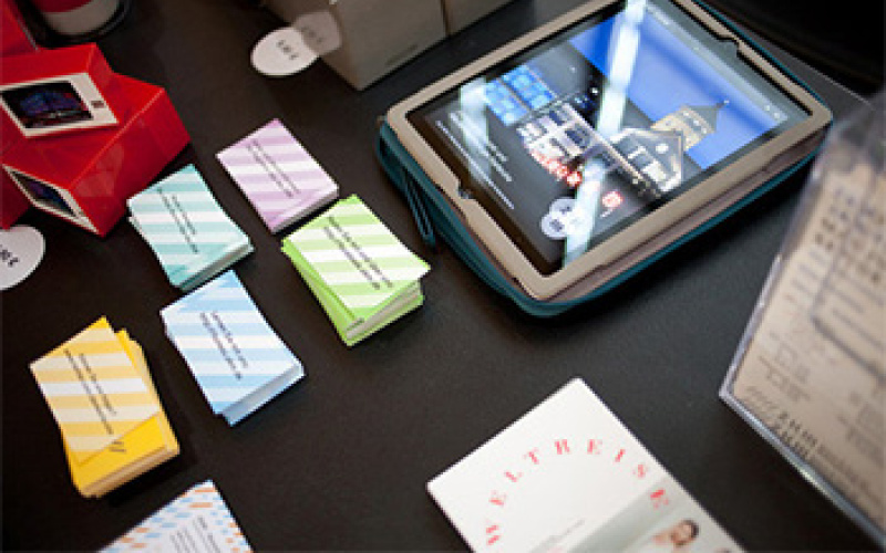 Numerous promotional materials at the stand of the ZKM. Colorful business cards and a tablet with a photo of the ZKM on it.