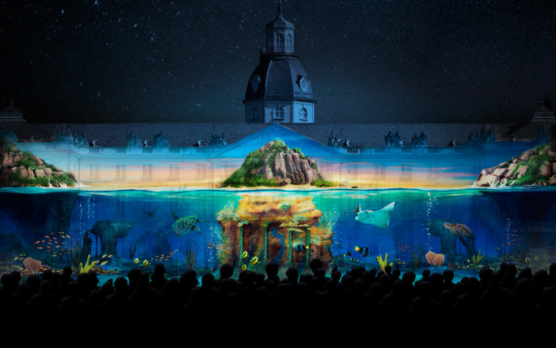 Das Foto zeigt ein Projection Mapping der Gruppe Maxin10sity auf dem Karlsruher Schloss. Zu sehen ist eine mystische Unterwasserwelt. 