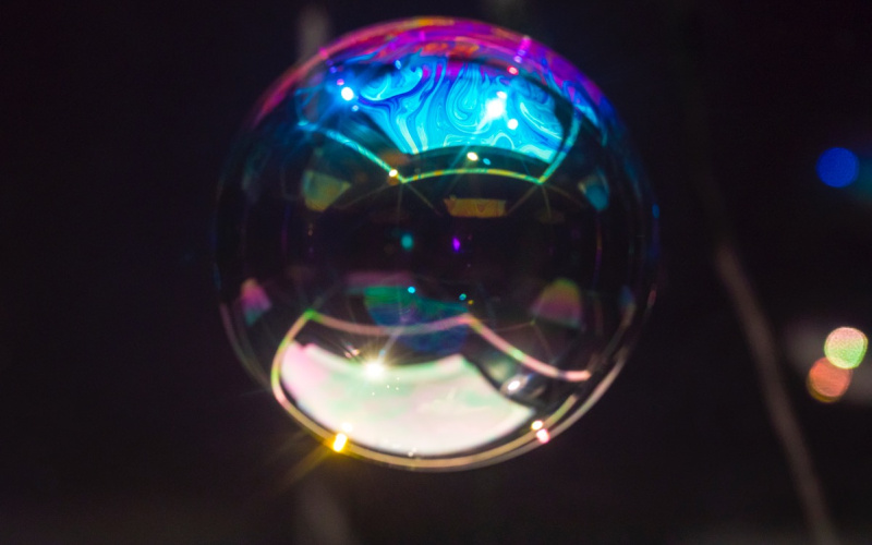 The photo shows a sphere similar to a huge soap bubble in front of a black background.