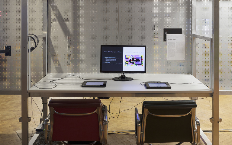 Ein Schreibtisch mit Monitor und zwei Stühlen